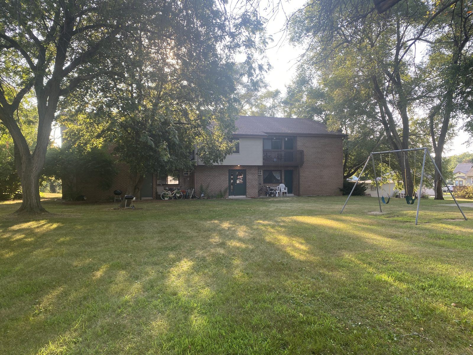 The Hummel Street building seen across its lawn, shaded by mature trees, with a swing set beside the yard.