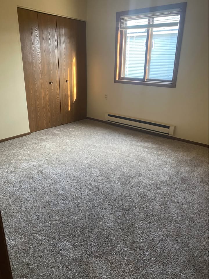 Carpeted bedroom with a wide closet and a bright window