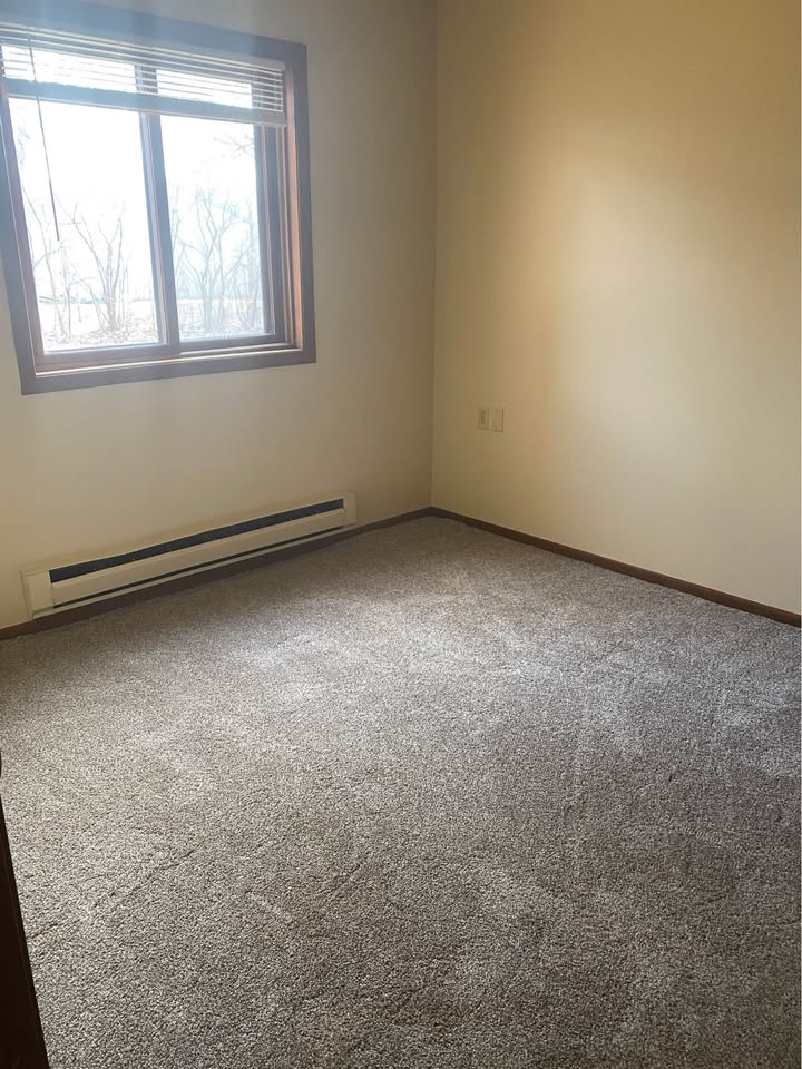 Carpeted bedroom with a corner window and baseboard heat